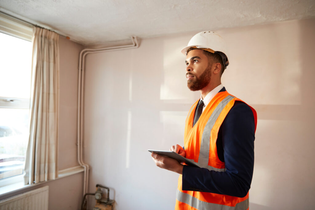 Property surveyor inspecting room with tablet during building assessment