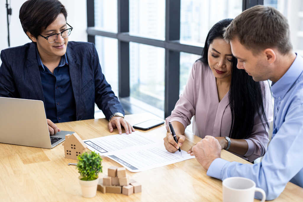 Property adviser reviewing contract paperwork with couple during consultation