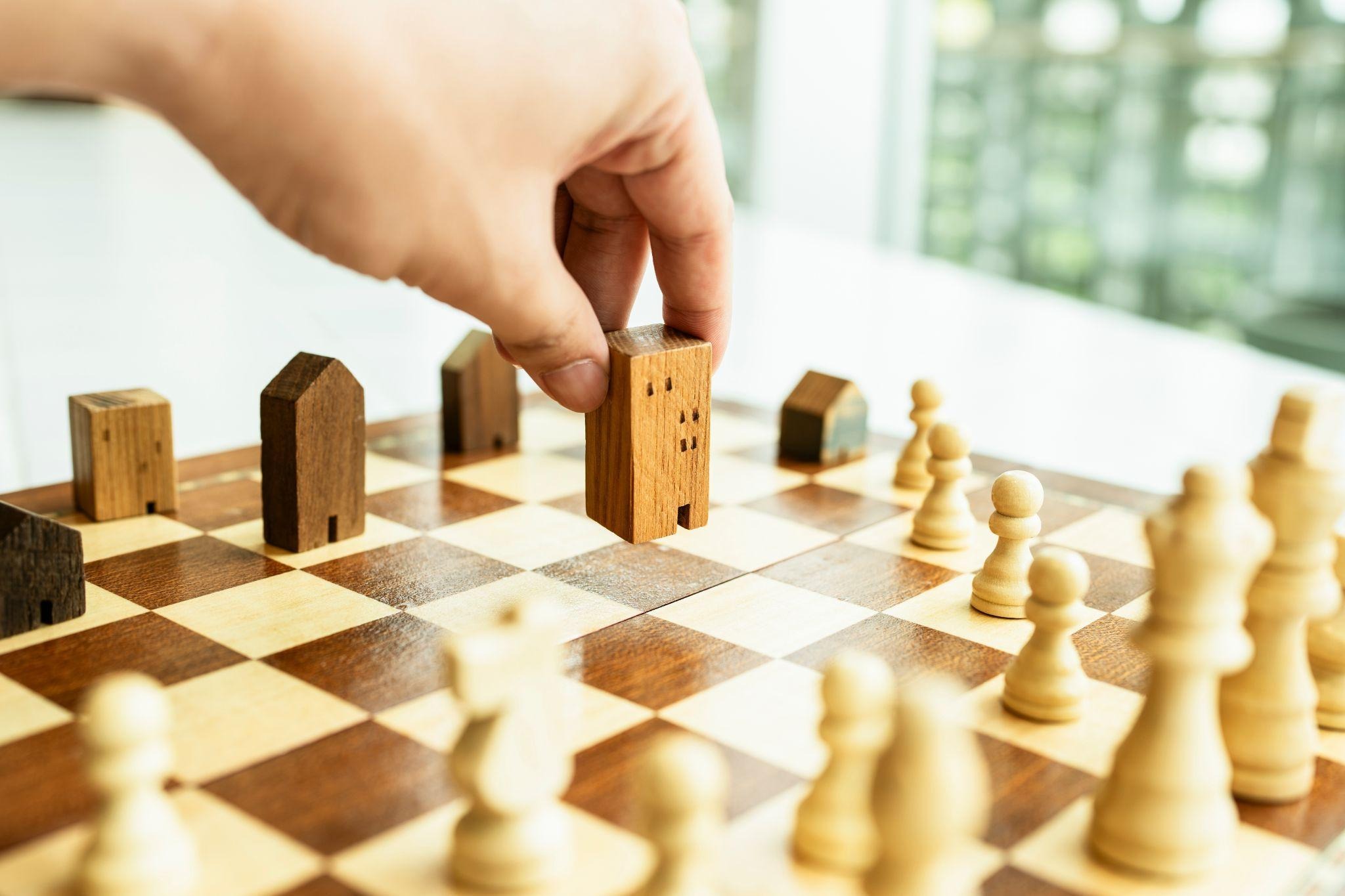 Wooden house pieces and chess pieces representing the property conveyancing process